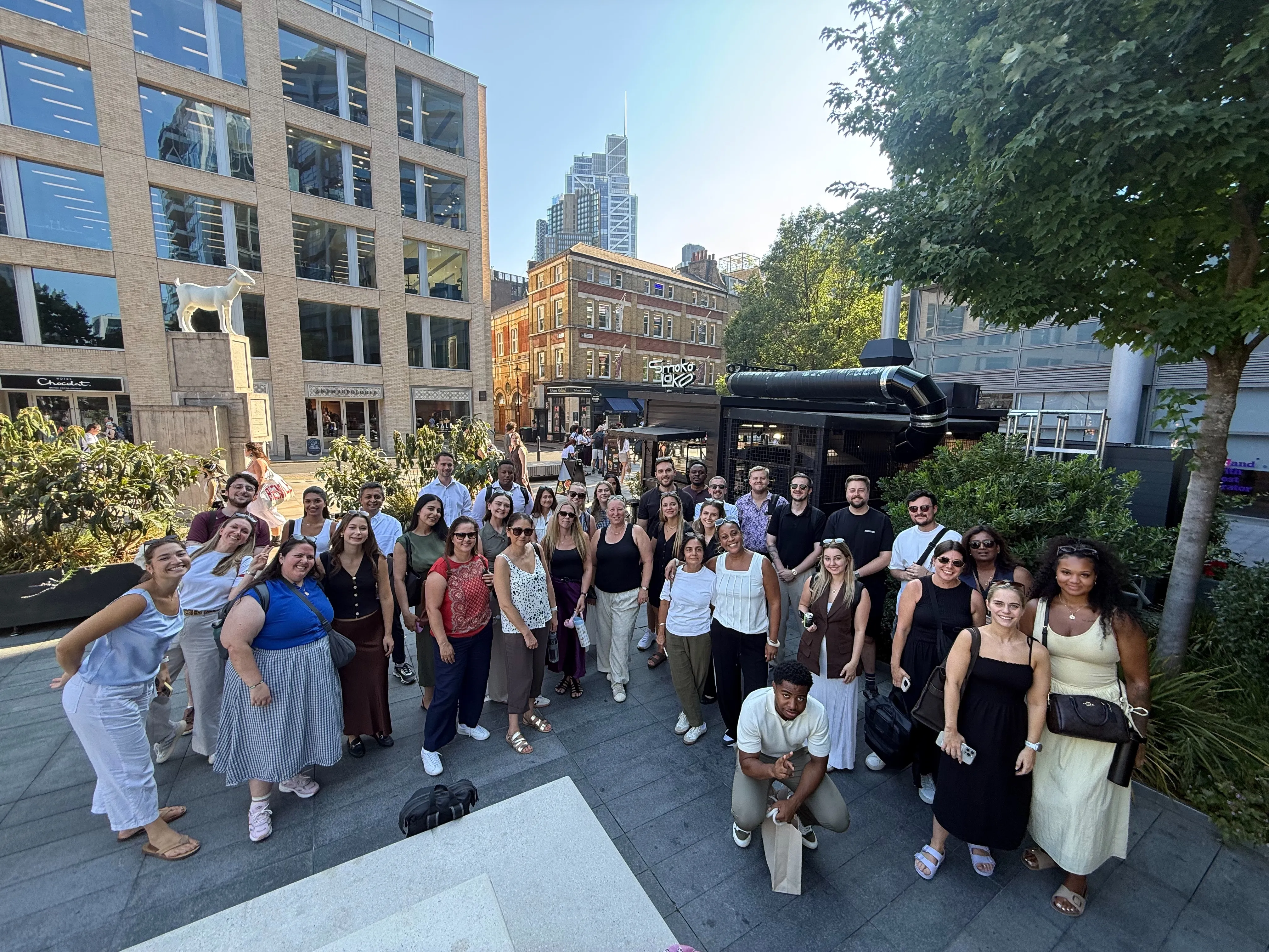 A large corporate team poses together outdoors in Shoreditch